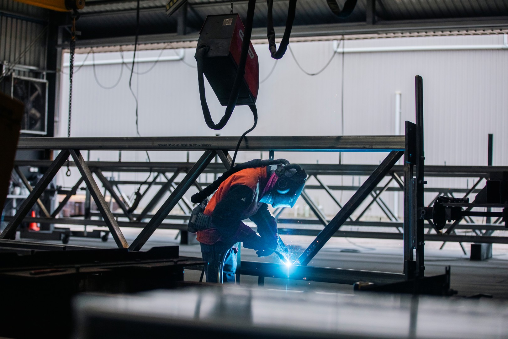 Long shot of TechSpan team member welding structural steel in the workshop