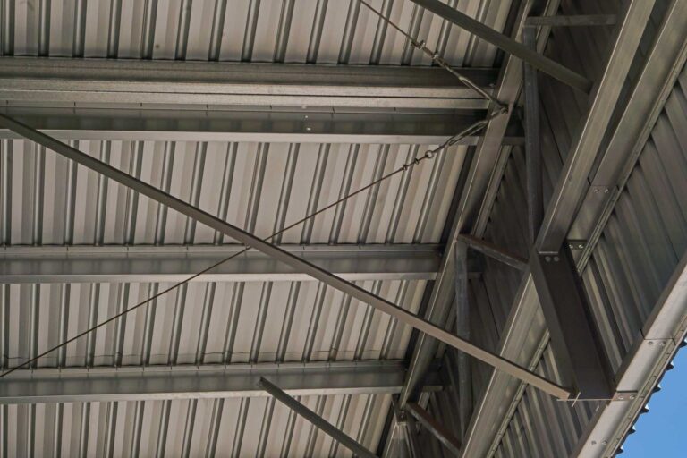 Looking up inside a shed showing structural steel beams and metal roof cladding
