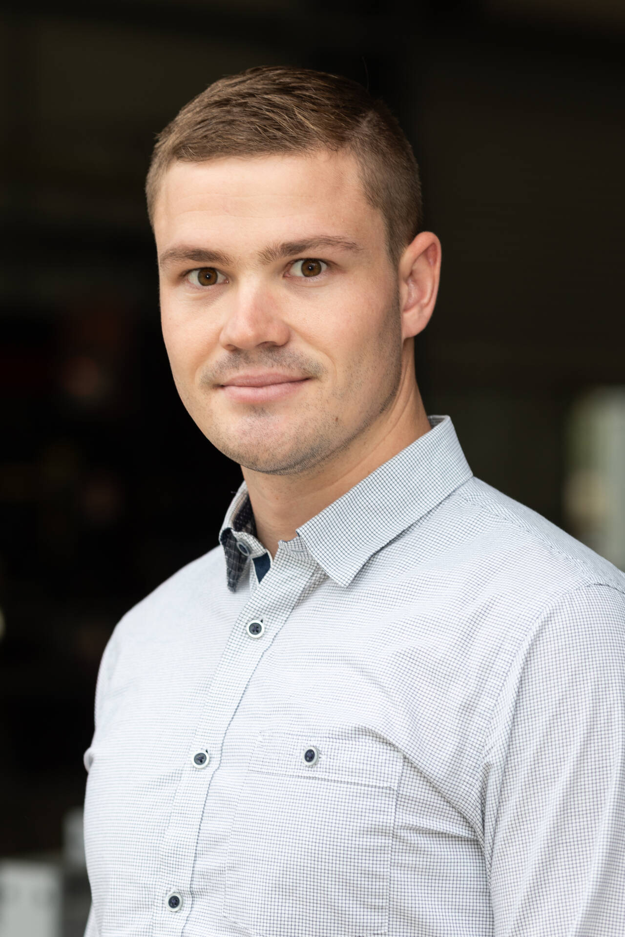 Portrait of George Ovenden from TechSpan Building Systems standing in front of a workshop environment wearing a light business shirt.