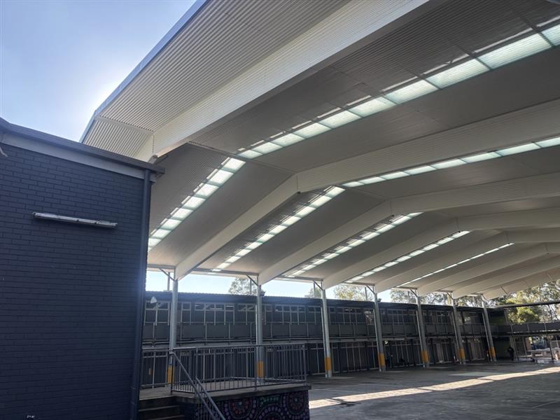 Side view of a large school COLA featuring a clear-span steel structure, insulated roof system and translucent roof panels for natural daylight.