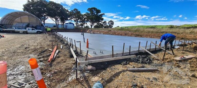 Newly poured concrete slab for an agricultural shed, with formwork and footing reinforcement in place.