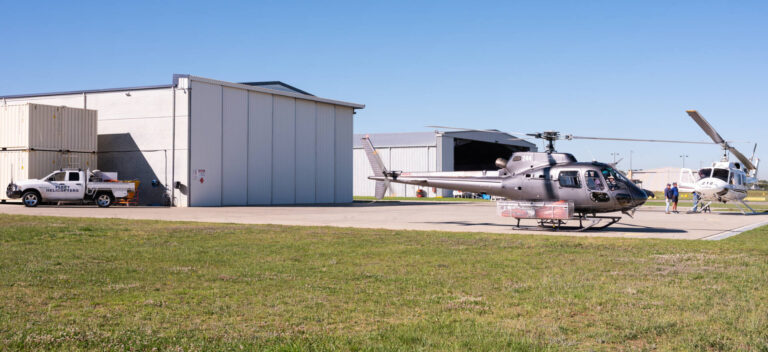 Helicopter parked outside a large aircraft hangar in Australia