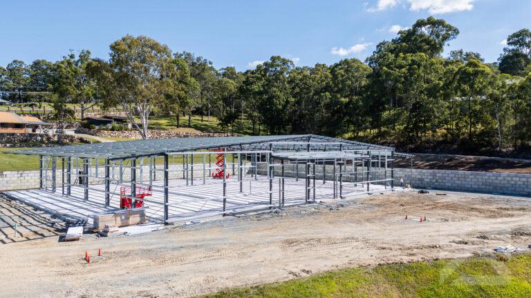 Aerial view of a structural steel building frame being erected on a concrete slab.